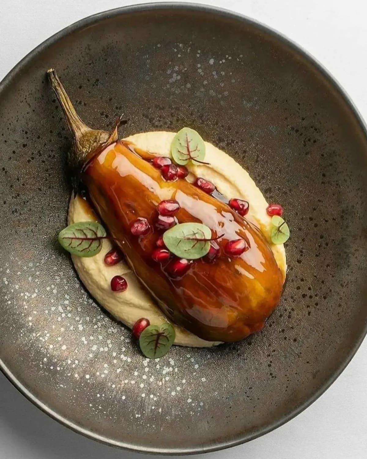 Glasierte Aubergine auf Hummus mit Granatapfelkernen, sinnbildlich für unsere vegetarischen Gerichte